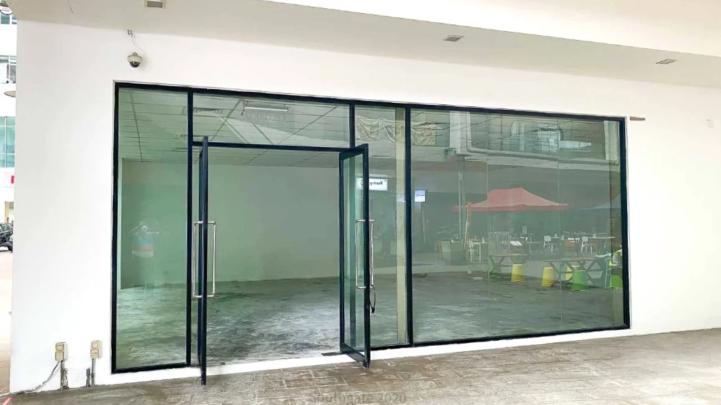 Exterior type: commercial space; features: glass facade, double glass doors, metal frame, concrete flooring, visible outdoor seating area, canopy over outdoor area, surrounding greenery, modern architectural design; style: modern.